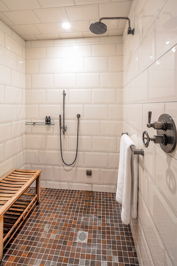Shower with white tile and bench